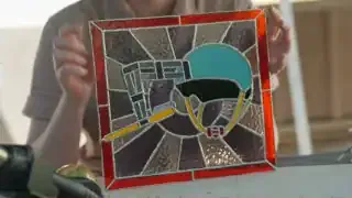 Simone Giertz holds up a stained glass representation of her original toothbrush helmet invention.