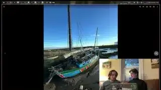 A colorful boat, named Molly, sits beached on muddy ground next to a body of water.