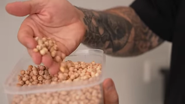 A close-up of Andy's hand holding dried chickpeas, which he uses as pie weights for blind baking pastry.