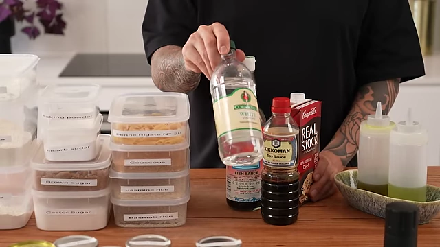 A bottle of distilled white vinegar, recommended as a versatile and inexpensive pantry staple for pickling and cleaning.