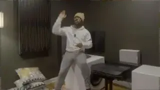 The speaker comparing the effect of overhead speakers (gesturing up) versus traditional surround speakers (gesturing around him) in a home theater setup.