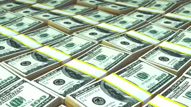 Stacks of US dollar bills, representing money as a fundamental economic convention.