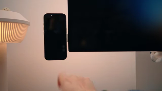 An iPhone mounted to a monitor with a charger, showing how it can be tucked away.