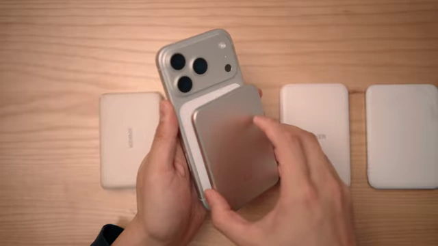 A series of increasingly slim MagSafe portable batteries being compared on a table next to an iPhone.