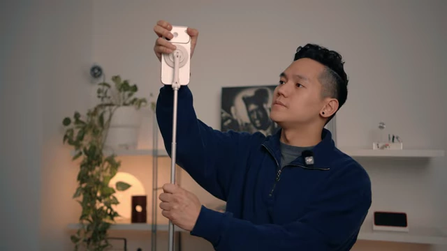 A person extending a tall, spring-loaded MagSafe tripod for their iPhone, demonstrating its quick setup.