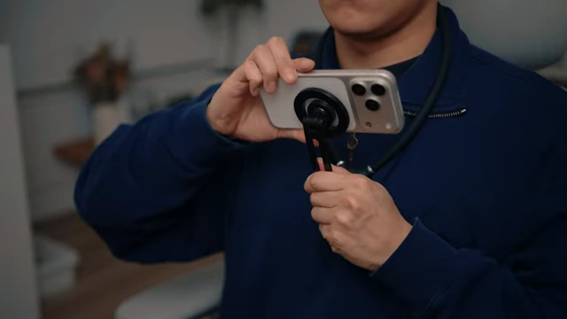 A person wearing an iPhone neck rig to capture a point-of-view shot while working.