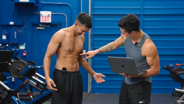 Nimesh showcasing his visible abdominal muscles as the instructor points to them, highlighting the successful outcome of his fat loss journey.