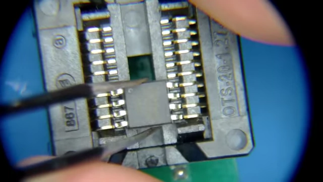 The desoldered flash chip being precisely placed into the universal programmer's adapter under a microscope.
