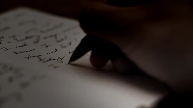 A close-up of a hand writing in a diary, representing Victor Neuburg's personal journal entries