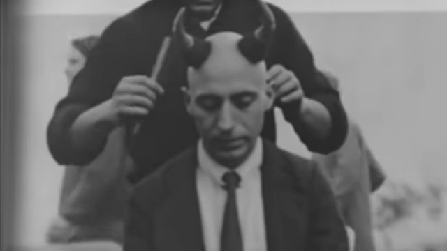 A black and white photo shows Crowley shaving Neuburg's head, leaving two small horns, a symbolic act of degradation