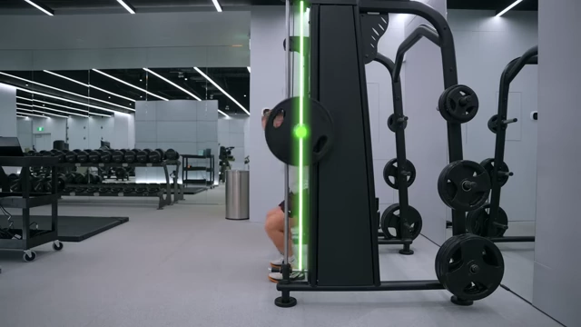 An animated graphic illustrates the straight bar path of the Atlantis Smith Machine during a squat.
