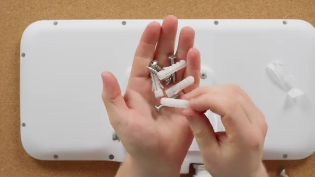 A hand holding large drywall anchors, included with the E7 Audience for wall installation.