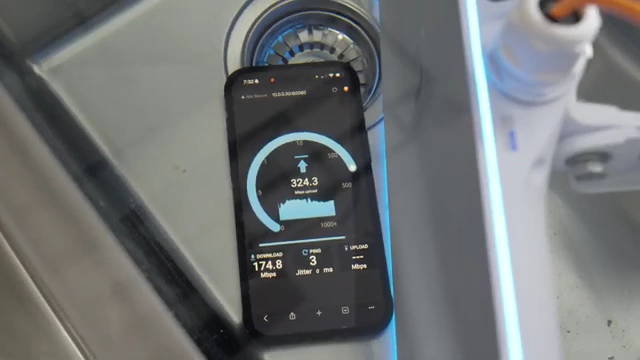 The E7 Audience submerged in a sink, actively running a speed test with a download speed of 174.8 Mbps.