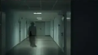 An illustrative image of a blurry, shadowy figure appearing at the end of a dimly lit hallway.