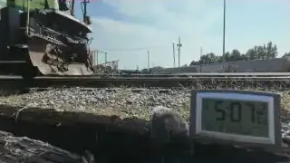 A microphone placed on the ground near the front of a train engine in a rail yard.