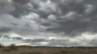 A wide shot of a stormy sky over a flat landscape, indicating a distant thunderstorm.
