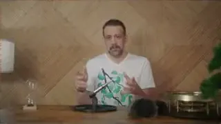 The speaker demonstrates using a plate to isolate a microphone from vibrations, placed on a rubber mat.
