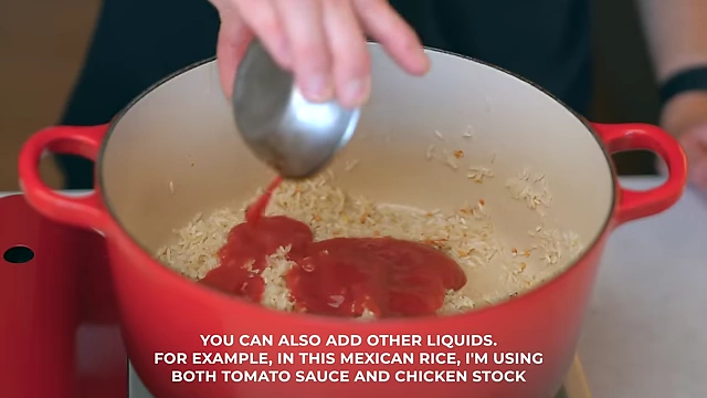 Tomato sauce and chicken stock being added to rice for a flavorful Mexican rice dish.
