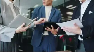 Three people in business attire engaged in a discussion, symbolizing a global team working together