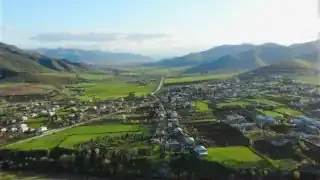 An aerial view of a verdant valley and distant mountains, representing a quiet, natural lifestyle