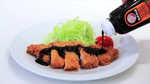 Slices of katsu (fried cutlet) drizzled generously with Tonkatsu sauce, accompanied by shredded cabbage.