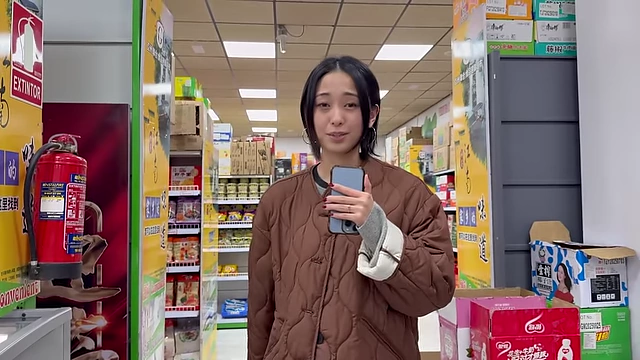 The speaker holding a smartphone while standing in a grocery store aisle, illustrating the option to find ingredients online.