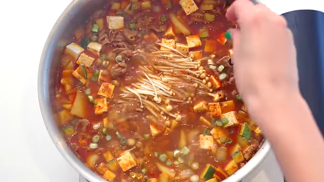 A hearty brisket doenjangjjigae stew simmering with various ingredients like beef, vegetables, tofu, and mushrooms.