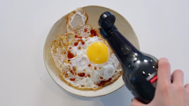 A bowl of warm rice topped with a crispy fried egg, drizzled with soy sauce and sesame oil.