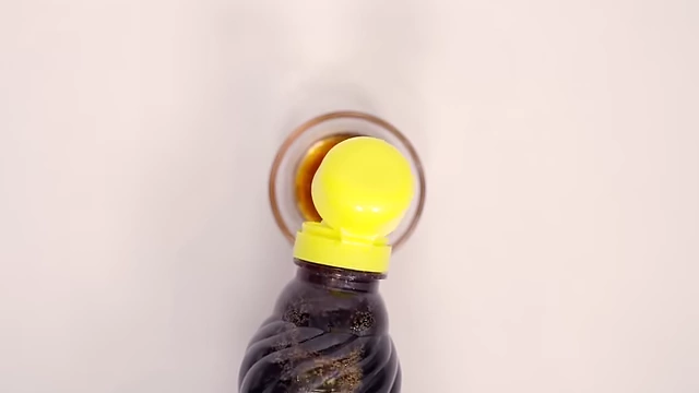 A dark amber liquid, green plum extract, being poured into a small bowl.