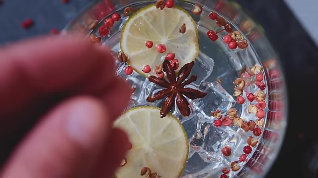 Sichuan peppercorns, lemon slices, and star anise in a glass, highlighting its unique citrusy and numbing flavor.