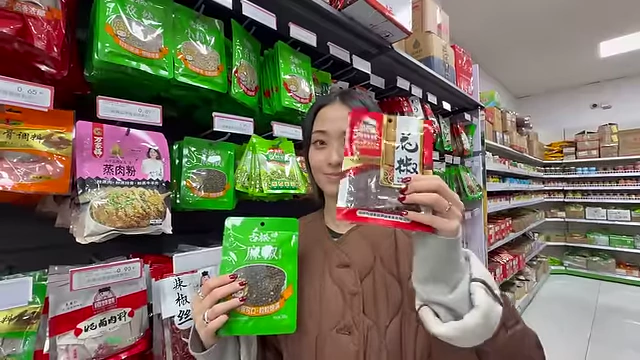 The speaker holding two packets, red and green Sichuan peppercorns, comparing their different flavor profiles.