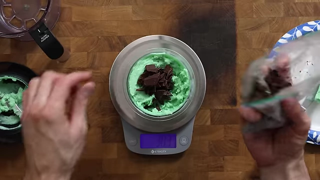 Adding 30g of homemade chocolate chips into a prepared hole in the processed mint ice cream.