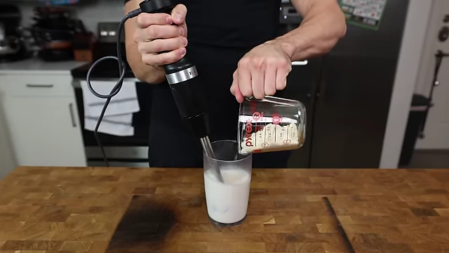 Blending wet and dry ingredients for the Oreo ice cream base using an immersion blender.