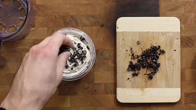 Topping the processed Oreo ice cream with chopped mini Oreos.