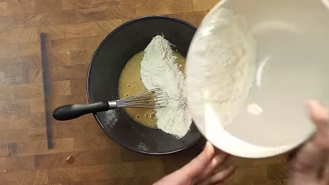 Gradually adding dry ingredients to wet ingredients for the cookie dough.