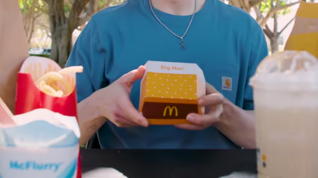 The presenter holding a McDonald's Big Mac in its box.