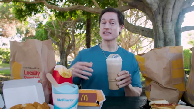 The presenter holding a McDonald's Caramel Frappe, describing it as the worst item.