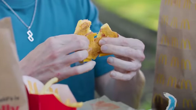 The presenter struggling to pull apart a McGriddle, expressing disgust at its texture and smell.