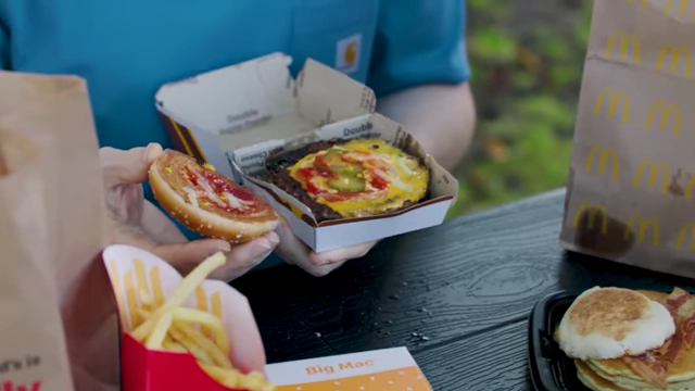 The presenter showing the inside of a Double Quarter Pounder with Cheese, revealing its contents.