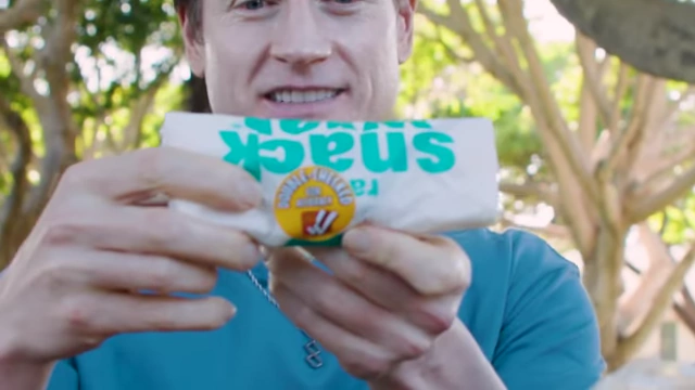 The presenter unwrapping a McDonald's Snack Wrap, noting its "double checked for accuracy" sticker.