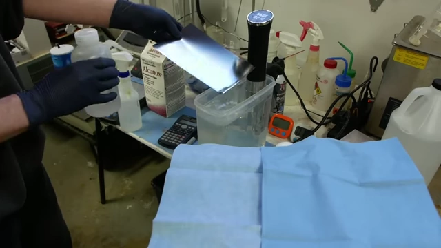 A clean sheet of metal undergoing a water break test, with water sheeting off uniformly, confirming a thoroughly cleaned surface.