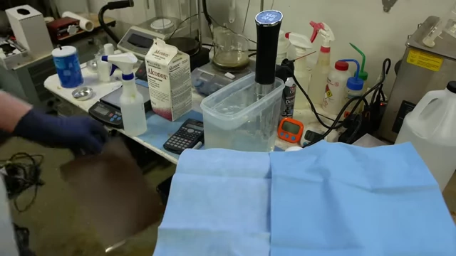 Hands drying a cleaned metal sheet with blue shop towels, emphasizing the importance of a lint-free drying process to prevent re-contamination.
