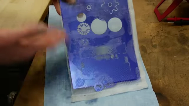 An etched metal panel still partially covered with photoresist, demonstrating the state of the parts before the final stripping step.