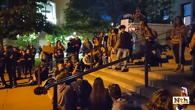 一群人在台阶上聚集，其中一人手持扩音器