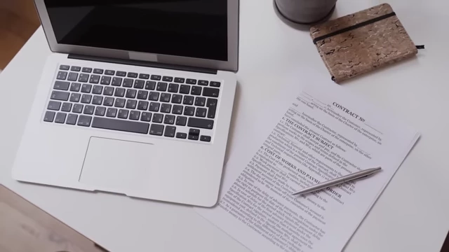 A laptop and a contract document, symbolizing the legal and bureaucratic aspects of property acquisition.