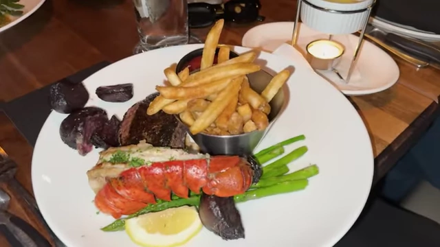 A rich meal of steak, lobster, and fries, representing a planned hedonic deviation, or treat meal