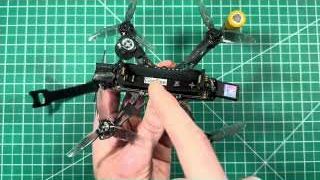 The reviewer points to the battery terminal ends, highlighting how they can loosen after crashes, leading to inconsistent power.