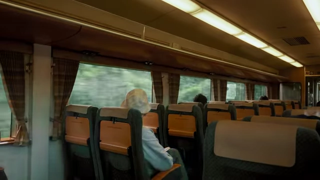 A train car interior with passengers, including Teo Crawford's grandma, looking out the window at the scenery.