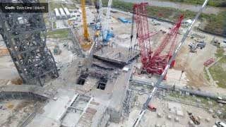 An aerial view of the Blue Origin Launch Complex 36-A during rebuilding, showing heavy cranes lifting the massive launch bridge.
