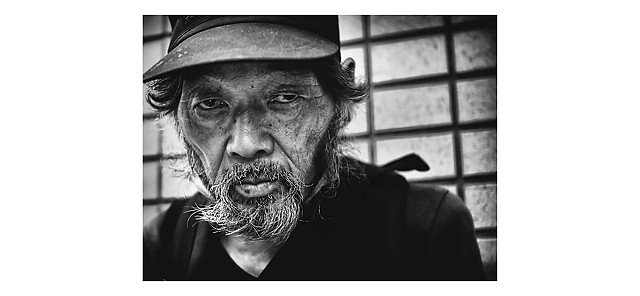 A man with an intense gaze and a cap looks directly at the viewer